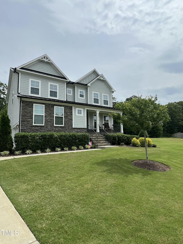 view of front of property with a porch, stone siding, and a front lawn