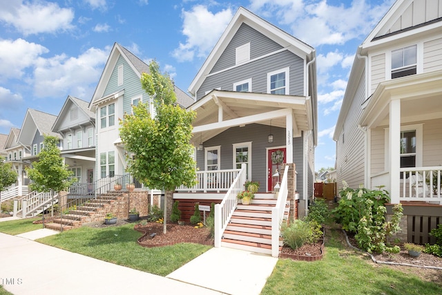 view of front of property with stairway, covered porch, board and batten siding, a front lawn, and a residential view