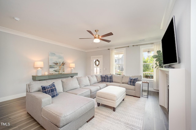 living area with light wood-type flooring, crown molding, a ceiling fan, and baseboards