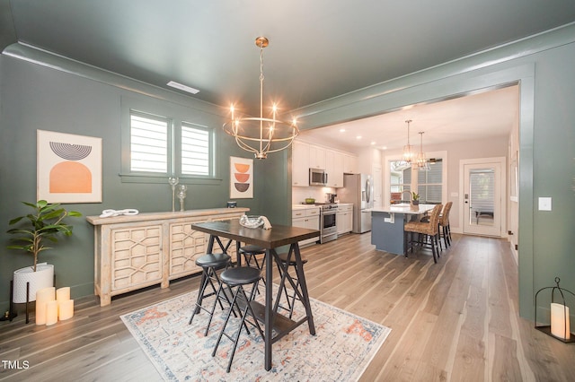 dining space featuring a chandelier, light wood-type flooring, baseboards, and recessed lighting