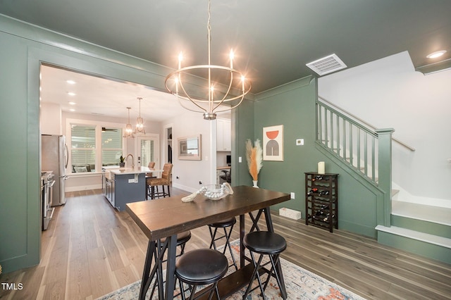 dining room with a chandelier, stairs, and wood finished floors