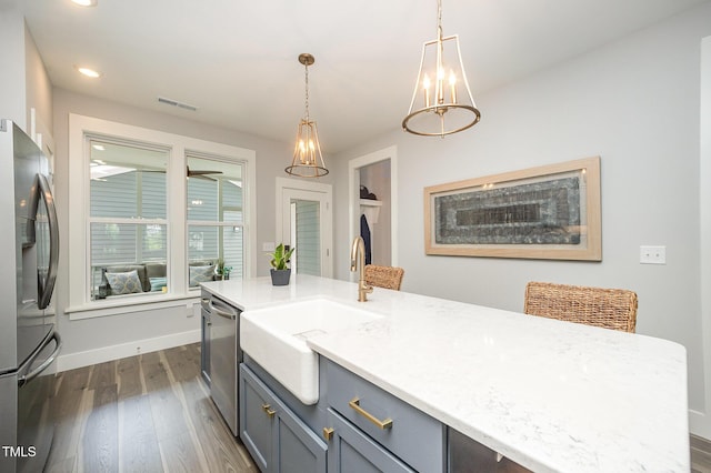 kitchen with appliances with stainless steel finishes, a sink, dark wood-style floors, baseboards, and decorative light fixtures