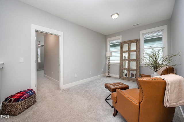 sitting room with baseboards and light colored carpet