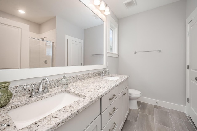 bathroom featuring a stall shower, toilet, baseboards, double vanity, and recessed lighting