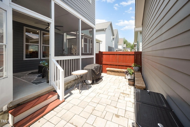 view of patio featuring fence, area for grilling, and a sunroom