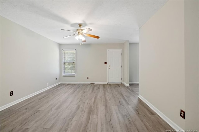 empty room featuring a ceiling fan, wood finished floors, baseboards, and a textured ceiling