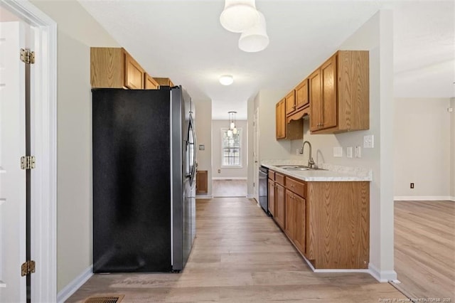 kitchen with stainless steel refrigerator with ice dispenser, a sink, light wood-style floors, light countertops, and baseboards