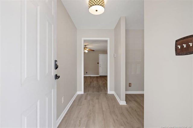 hallway featuring light wood finished floors and baseboards