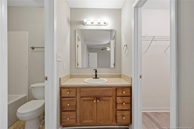 bathroom with toilet, vanity, a spacious closet, and a tub