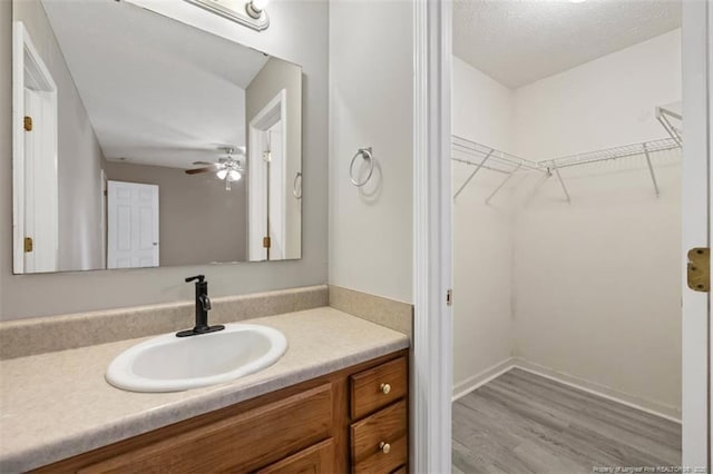 bathroom featuring vanity, a spacious closet, wood finished floors, and ceiling fan