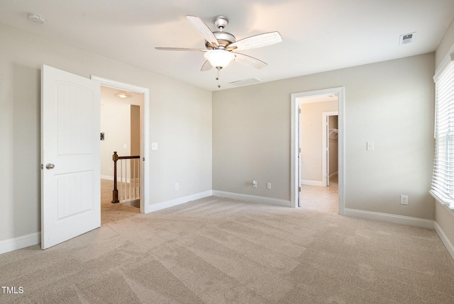 111 Laporte Path, Garner, NC 27529 - unfurnished bedroom with light carpet, a walk in closet, multiple windows, and a ceiling fan