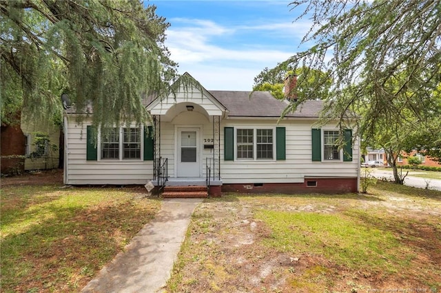 view of front of property with crawl space, a front lawn, a chimney, and a shingled roof