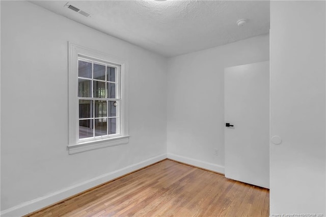 spare room with wood finished floors, baseboards, and a textured ceiling