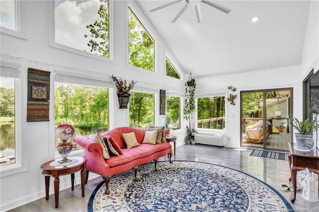 sunroom / solarium featuring high vaulted ceiling, plenty of natural light, baseboards, and wood finished floors
