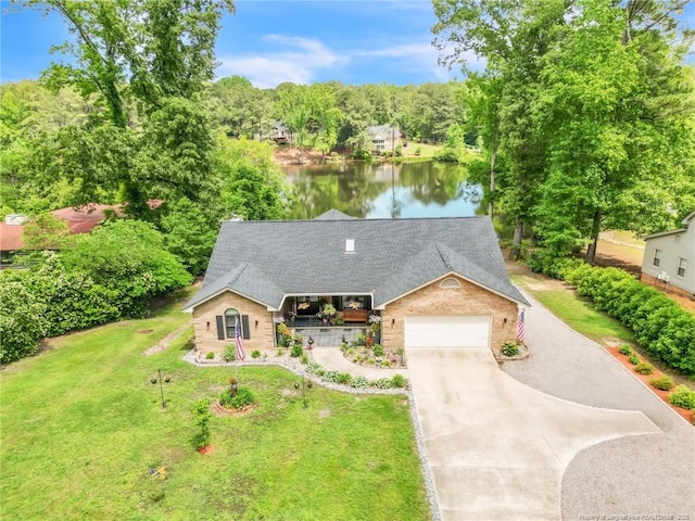 ranch-style home featuring concrete driveway, covered porch, an attached garage, a front yard, and a water view