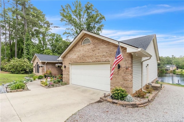 view of front of property featuring brick siding, an attached garage, driveway, a water view, and a shingled roof