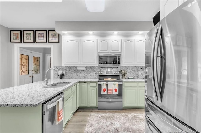 kitchen featuring appliances with stainless steel finishes, a sink, green cabinetry, a peninsula, and white cabinetry