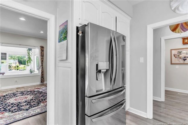 kitchen with stainless steel fridge, white cabinetry, light wood-style flooring, baseboards, and recessed lighting