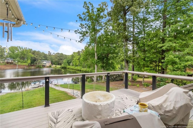 deck with a water view, a yard, grilling area, and view of scattered trees