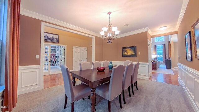 99 Grassy Creek Way, Chapel Hill, NC 27517 - dining room with ornamental molding, light carpet, a chandelier, a wainscoted wall, and a decorative wall