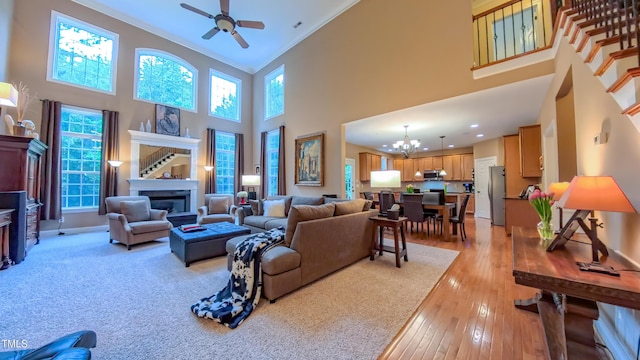 99 Grassy Creek Way, Chapel Hill, NC 27517 - living area featuring a glass covered fireplace, ceiling fan, a chandelier, a high ceiling, and light wood-type flooring