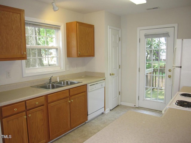 kitchen featuring white appliances, a sink, healthy amount of natural light, and light countertops