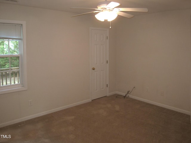empty room featuring a ceiling fan, healthy amount of natural light, carpet floors, and baseboards