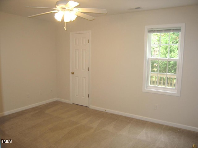 empty room with ceiling fan, light colored carpet, and baseboards