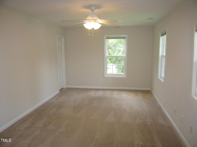 empty room with light carpet, a ceiling fan, and plenty of natural light