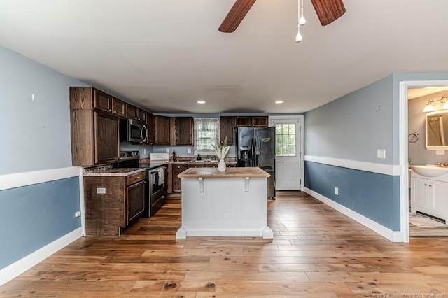 kitchen featuring stainless steel appliances, a sink, dark brown cabinets, ceiling fan, and light wood-style floors