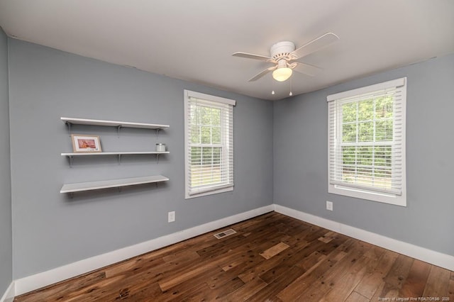 unfurnished room featuring dark wood-type flooring, plenty of natural light, and baseboards