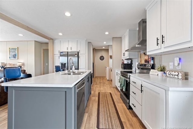 182 Ajax Dr, Saint Pauls, NC 28384 - kitchen with appliances with stainless steel finishes, wall chimney exhaust hood, a sink, light wood-type flooring, and light countertops