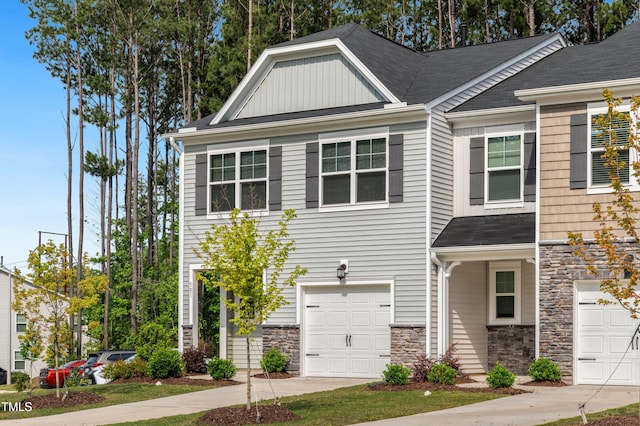 townhome / multi-family property with stone siding, a garage, board and batten siding, and concrete driveway