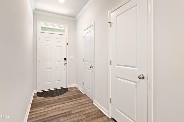 foyer entrance featuring wood finished floors, crown molding, and baseboards