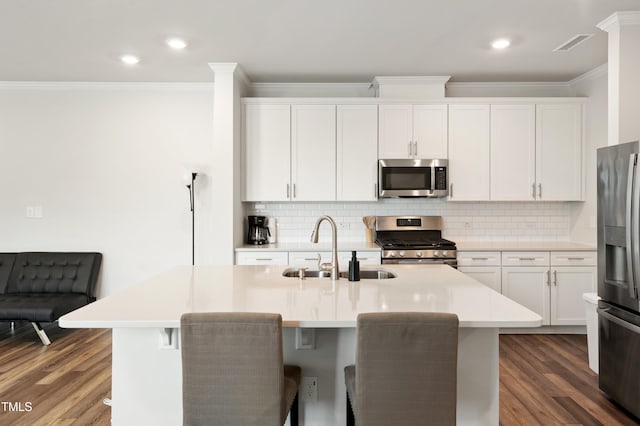 kitchen featuring stainless steel appliances, ornamental molding, a sink, dark wood-style flooring, and backsplash