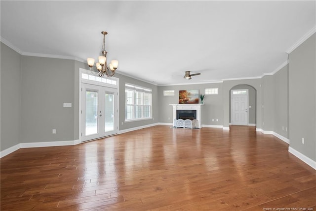 unfurnished living room with wood finished floors, ornamental molding, a chandelier, a ceiling fan, and baseboards