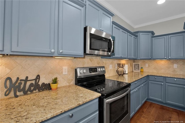 kitchen with appliances with stainless steel finishes, blue cabinetry, crown molding, light stone counters, and dark wood-style flooring