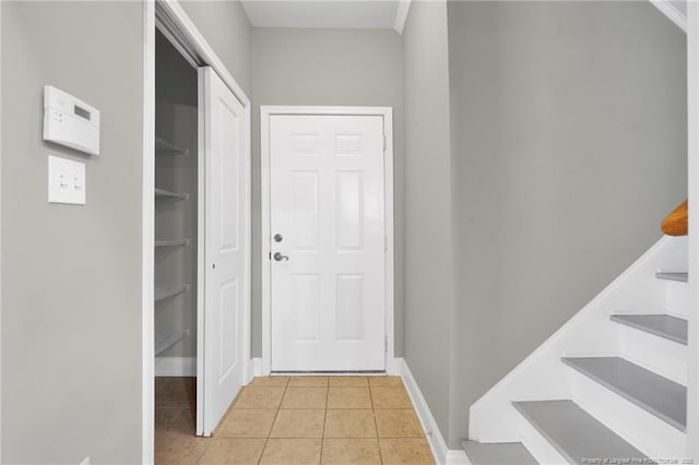 entryway with light tile patterned floors, stairs, and baseboards