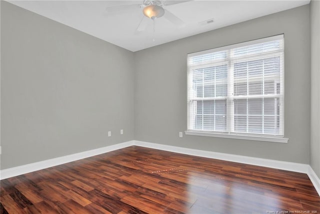 spare room featuring baseboards, dark wood-type flooring, and ceiling fan
