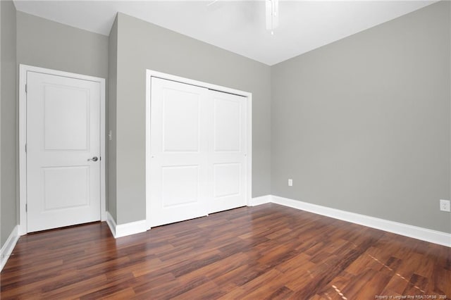 unfurnished bedroom with wood finished floors, baseboards, a closet, and ceiling fan