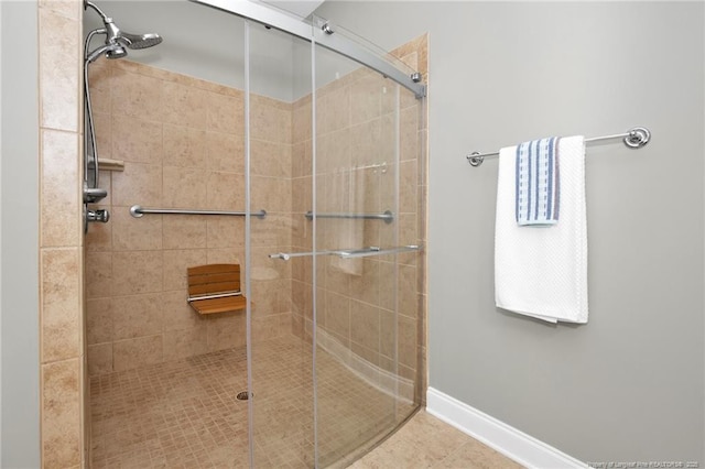 full bath with a shower stall, tile patterned flooring, and baseboards
