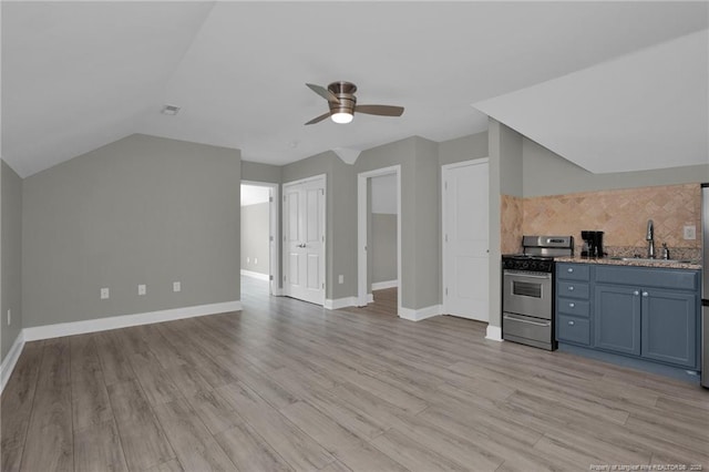 interior space featuring stainless steel range with gas stovetop, a sink, a ceiling fan, vaulted ceiling, and light wood-style floors