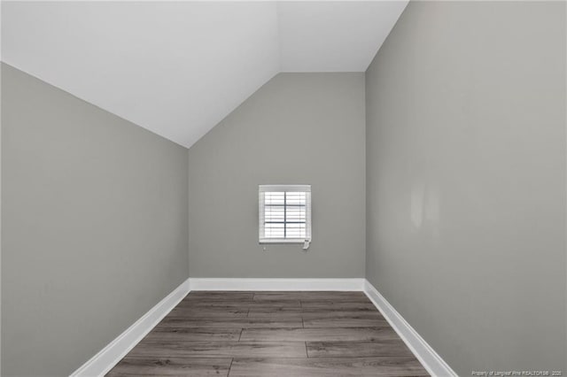 additional living space with vaulted ceiling, wood finished floors, and baseboards