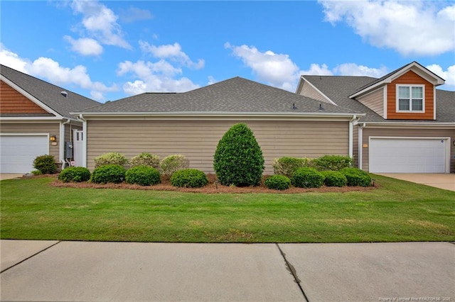view of side of property with driveway, a lawn, and roof with shingles