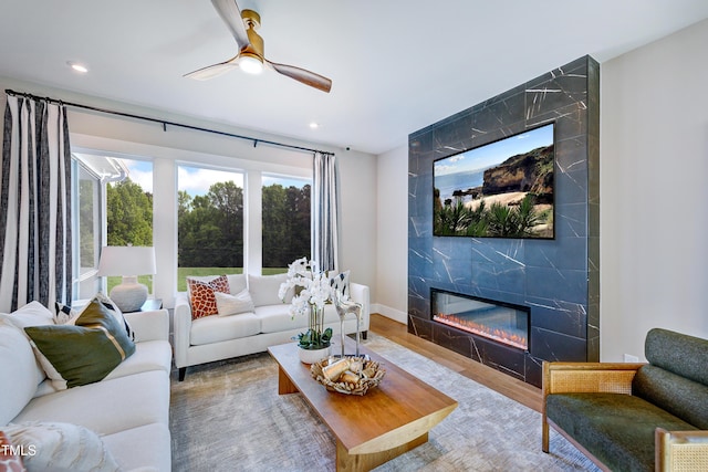 living area with a high end fireplace, wood finished floors, ceiling fan, and recessed lighting