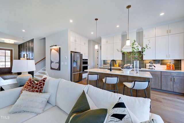 kitchen with stainless steel refrigerator with ice dispenser, open floor plan, light countertops, white cabinets, and decorative backsplash