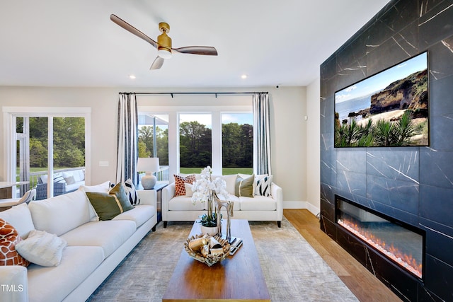 living room featuring plenty of natural light, wood finished floors, recessed lighting, a tile fireplace, and a ceiling fan