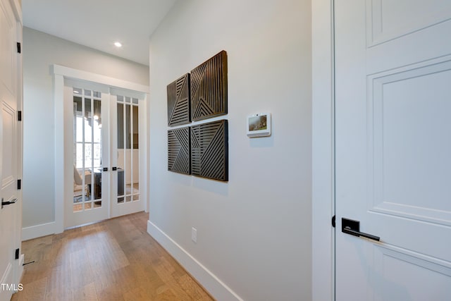 hall with baseboards, recessed lighting, light wood-style floors, and french doors