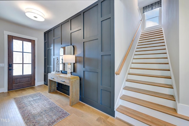 foyer entrance featuring healthy amount of natural light, stairs, baseboards, and light wood-style flooring