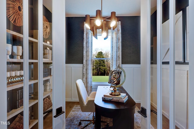 office with a chandelier, a decorative wall, a wainscoted wall, and wood finished floors
